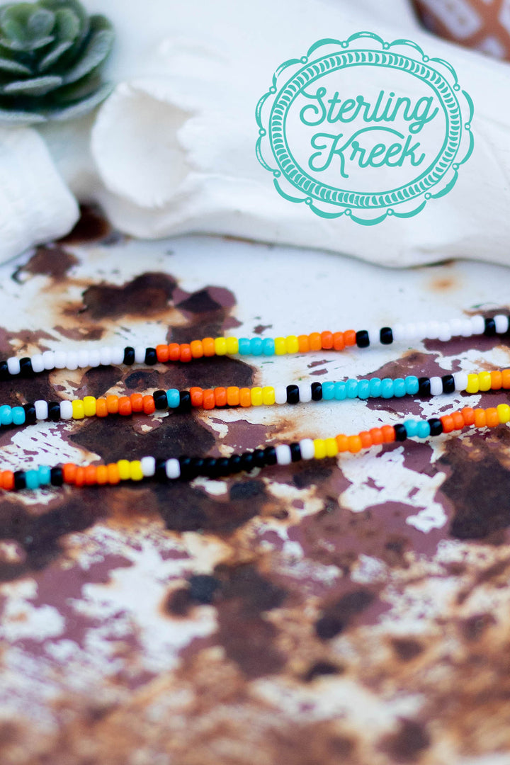 Simple Seed bead necklace with black, orange, turquoise, yellow, and white beads. This necklace is a perfect simple addition to any outfit!   16" with 2" extension chain  MSRP: $9+