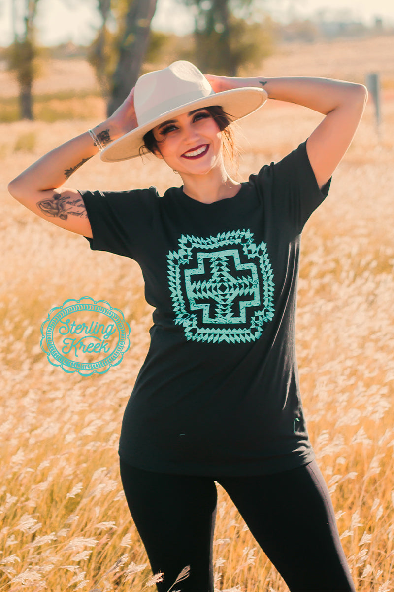 Who doesn't love a good Aztec tee? The black base of this shirt really makes the turquoise print POP! We hope you enjoy this shirt as much as we do!   Mariah is wearing a Small