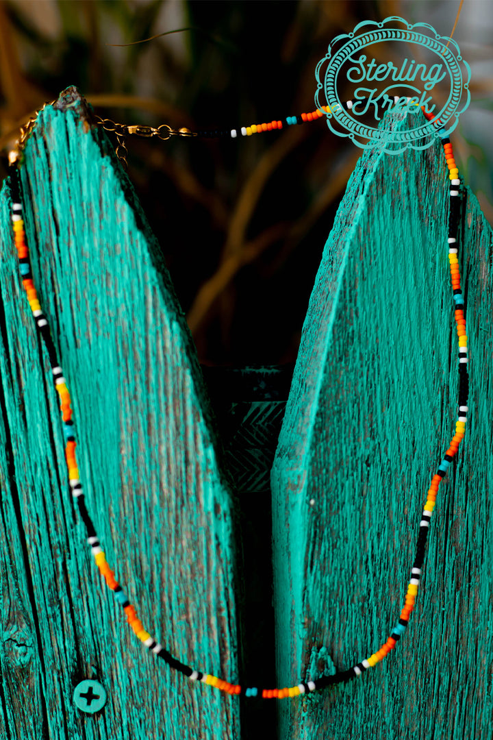Simple Seed bead necklace with black, orange, turquoise, yellow, and white beads. This necklace is a perfect simple addition to any outfit!   16" with 2" extension chain  MSRP: $9+